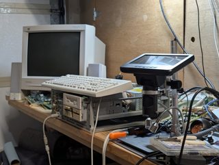 The bench: a ViewSonic CRT, a keyboard resting on the open PB686 chassis with its floppy drives, a USB microscope and a soldering station on a wooden shelf